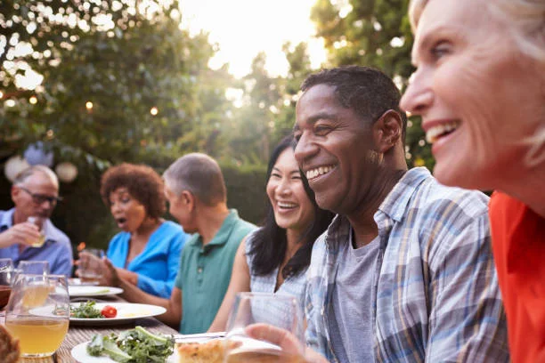 Group of friends smiling and talking over an outdoor dinner