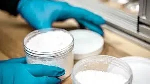 Gloved hands handling supplement ingredients in a production facility